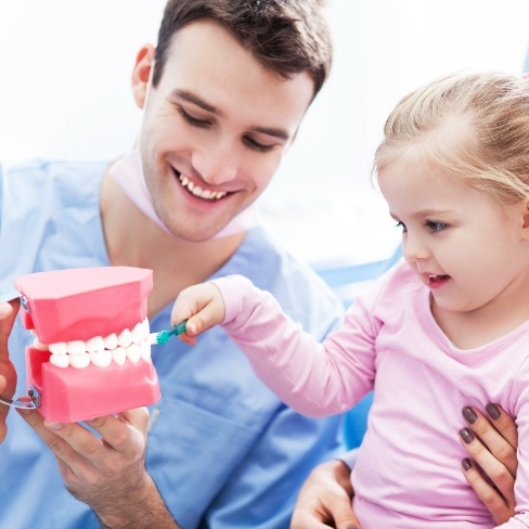 Dentist showing child how to brush teeth