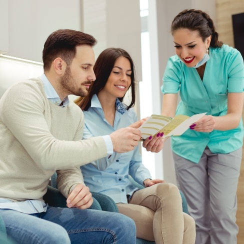 Pediatric dental team member and parents reviewing dental insurance coverage