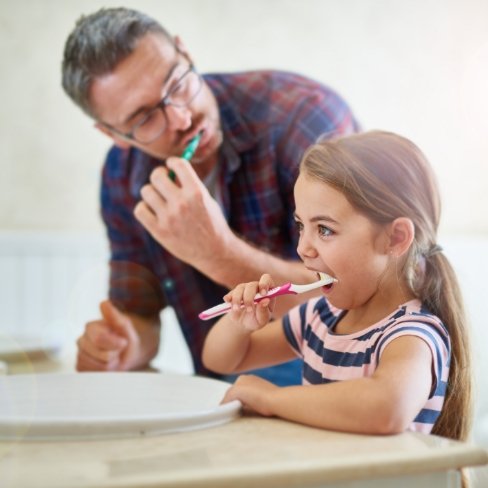 Father helping child with at home dental care