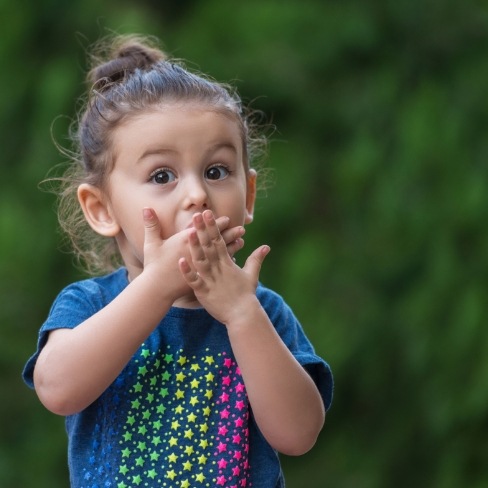 Child in need of emergency dentistry covering her mouth