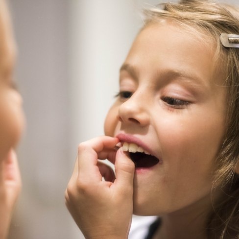 Child pulling a loose baby tooth