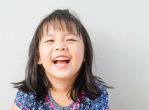 smiling child with curly hair in the dentist’s chair