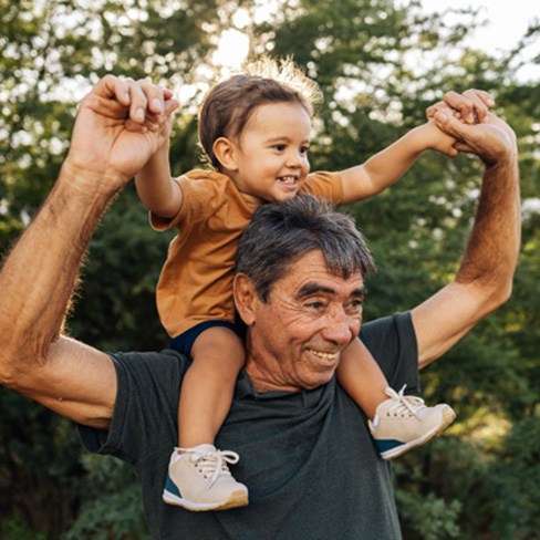 a grandparent with their grandchild on his shoulders