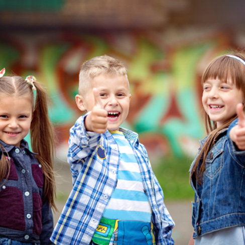 Three happy kids giving thumbs-up gesture