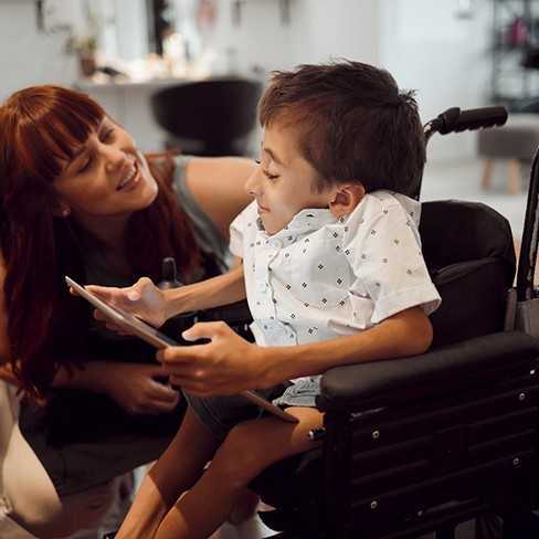 young boy in wheelchair reading from tablet 