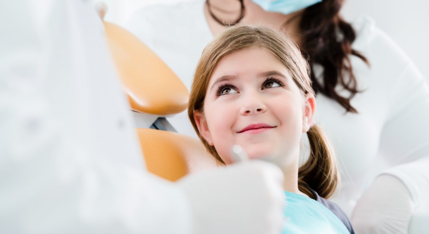 Child smiling at pediatric dentist in state of the art dental office